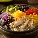 Close-up of a chicken and rice burrito bowl with fresh ingredients and vibrant colors.