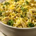 Close-up of chicken broccoli casserole with noodles, topped with cheese and herbs.