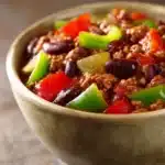 Close-up of Chili Con Carne with beans and spices in a bowl, garnished with herbs.
