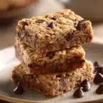 Close-up of chocolate chip oatmeal cookie bars with visible chocolate chips and a golden-brown texture.