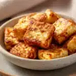 Crispy air fryer tofu pieces on a white plate with a clean background.