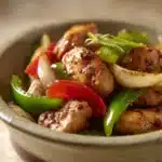 Close-up of Black Pepper Chicken with creamy sauce and herbs on a clean plate.