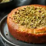 Close-up of a greek yogurt pistachio cake with creamy texture and pistachio topping.