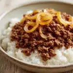 Close-up of a delicious ground beef dish cooked on the stove top, garnished with herbs.