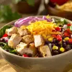 Close-up of a high protein chicken enchilada bowl with vibrant toppings and creamy sauce.