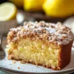 Close-up of a lemon coffee cake with a crumbly topping and bright lighting.