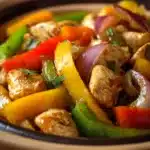 Close-up of a vibrant Mexican chicken stir-fry with colorful vegetables and herbs.
