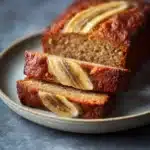 Close-up of a moist banana bread with a golden crust, showcasing its soft texture.