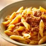Close-up of one pot pasta with ground beef in a creamy sauce, garnished with herbs.