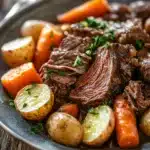 Close-up of a slow cooker pot roast dinner with vegetables and gravy.