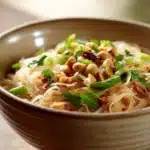 Close-up of spicy noodles with vibrant sauce and garnishes
