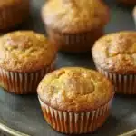 Close-up of freshly baked banana muffins on a white plate with a minimal background.