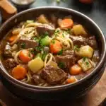 Close-up of beef stew and noodles in a crock pot with a warm, appetizing appearance.