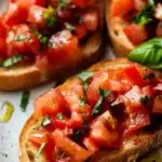 Close-up of delicious bruschetta with fresh tomatoes and herbs on a wooden board.