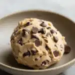 Close-up of chocolate chip cookie dough with visible chocolate chips on a clean surface.