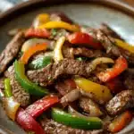 Close-up of crock pot beef pepper steak with vibrant peppers and tender beef slices.