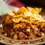 Close-up of frito pie casserole with ground beef and corn chips in a baking dish.