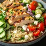 Close-up of a high protein chicken quinoa salad with fresh greens and colorful vegetables.