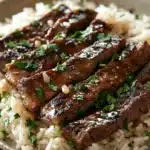 Close-up of honey butter garlic steak and rice skillet with bright, warm lighting.