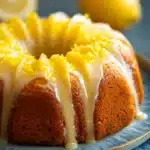 Close-up of a lemon cake with a slice cut out, showcasing its moist texture and vibrant yellow color.