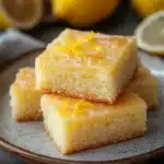 Close-up of lemon cake squares with a bright, warm background.