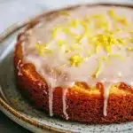 Close-up of a lemon cake with a slice cut out, showcasing its moist texture and vibrant yellow color.