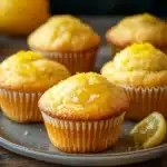 Close-up of lemon muffins with lemon curd on a white plate, showcasing vibrant yellow and soft textures.