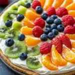 Close-up of a peanut butter cookie fruit pizza with vibrant fruits on top
