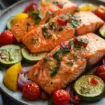 Close-up of a sheet pan with roasted salmon and colorful vegetables