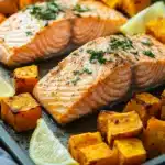 Close-up of sheet pan salmon with sweet potatoes and vegetables in bright natural light.