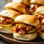 Close-up of slow cooker zesty BBQ chicken sliders with a clean background.