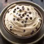 Close-up of chocolate chip cookie frosting with visible chocolate chips and creamy texture.