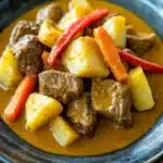 Close-up of slow cooker beef yellow curry with creamy sauce and herbs