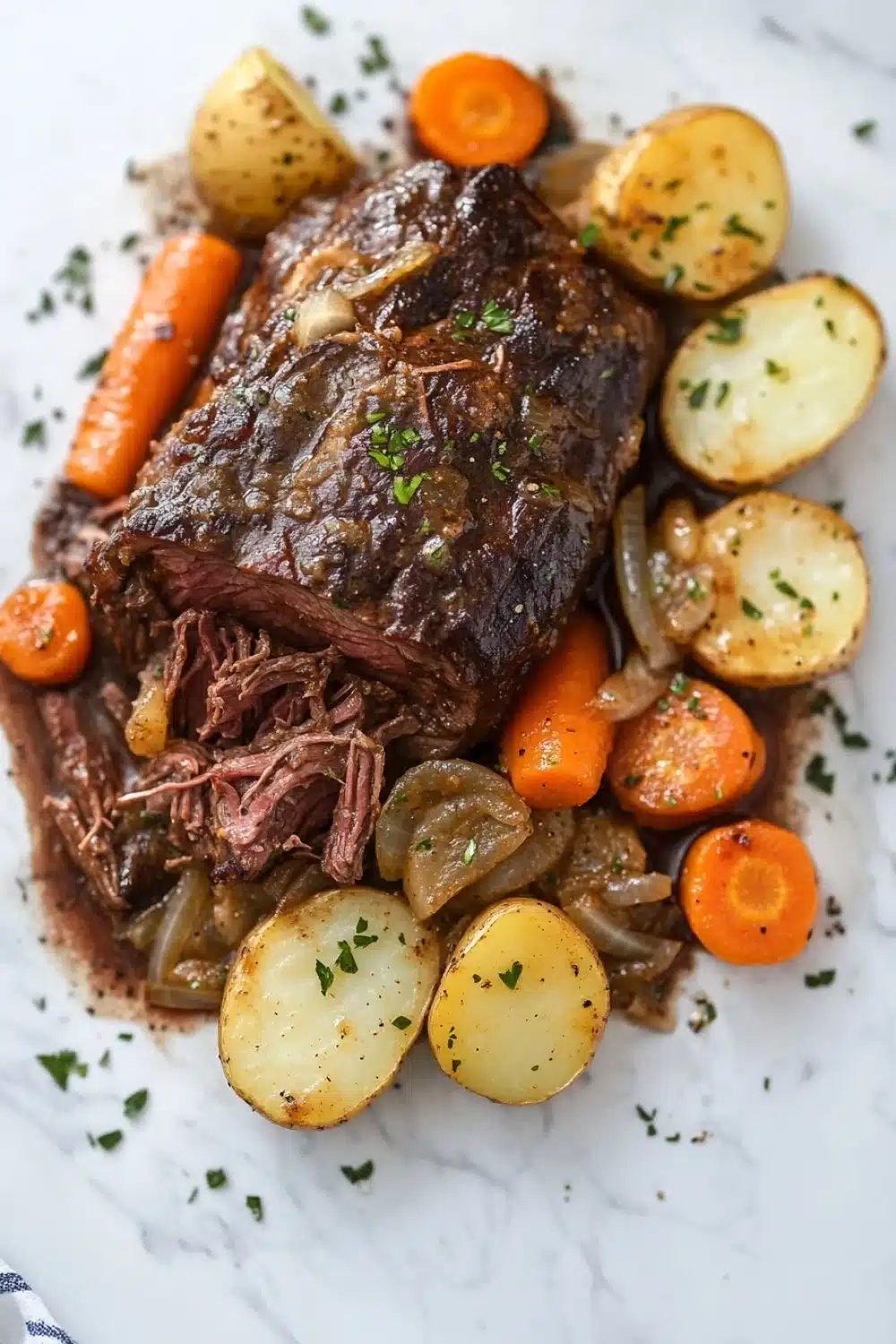3 packet pot roast slow cooker - the image shows a plate of food with a large piece of roast beef on top. the roast beef is cooked medium-rare and has a dark brown color. it is garnished with chopped herbs and is surrounded by sliced carrots, potatoes, and onions. the plate is white and there is a blue and white striped napkin on the side. the food appears to be freshly cooked and ready to eat.