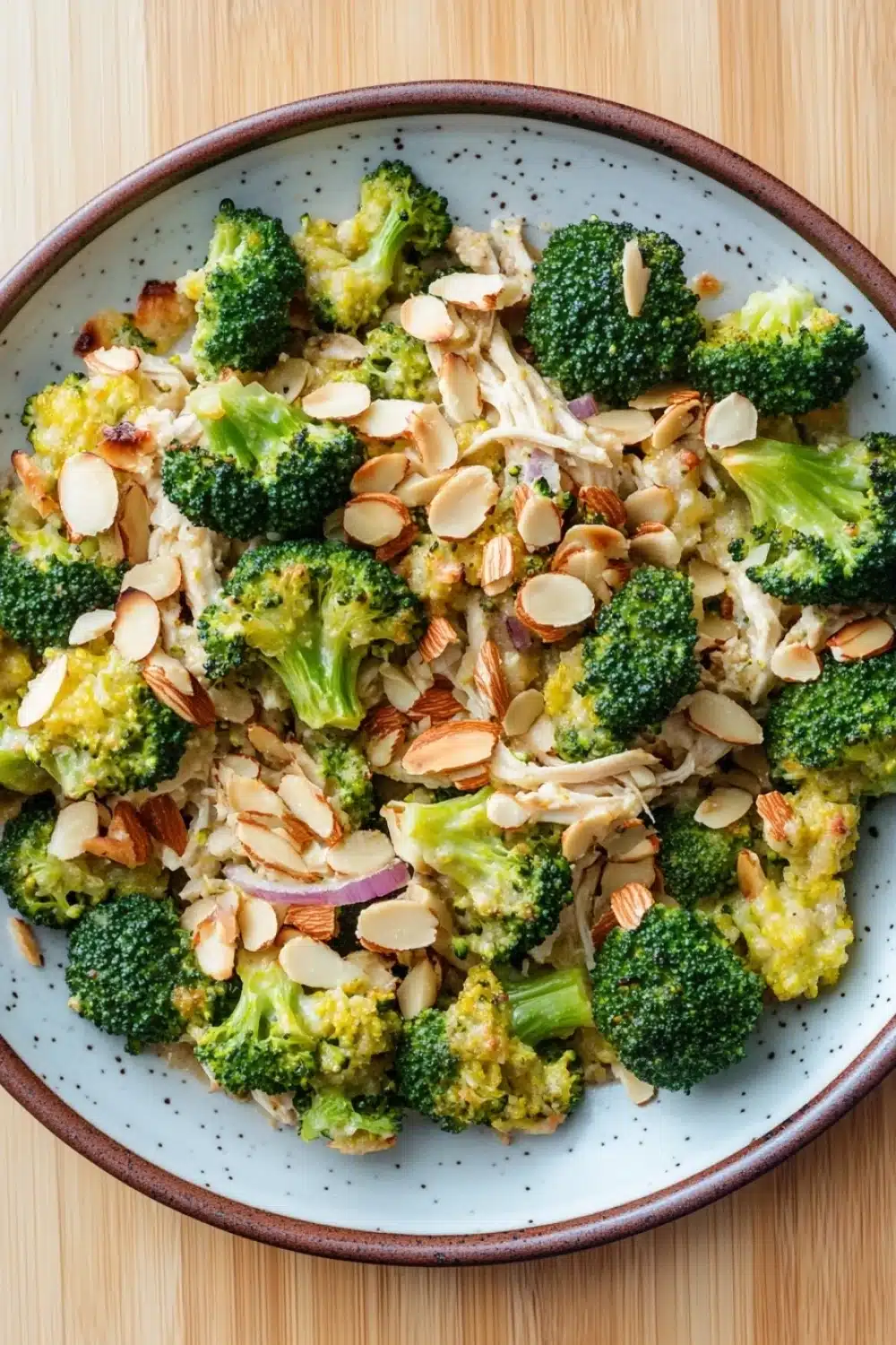 Chicken broccoli casserole whole 30 - the image is a close-up of a plate of food. the plate is white with a brown rim and is placed on a wooden table. the food appears to be a dish made with broccoli florets, sliced almonds, and other ingredients. the broccoli is bright green and looks fresh and healthy. the almonds are scattered throughout the dish, adding a crunchy texture and nutty flavor. the other ingredients in the dish are also visible, but they are not clearly visible. the overall appearance of the dish is fresh and appetizing.