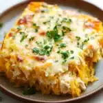 Cheesy chicken spaghetti squash casserole jar of lemons - the image shows a slice of spaghetti squash casserole on a brown plate. the dish appears to be freshly baked and has a golden brown crust on top. the top of the dish is covered in melted cheese and garnished with fresh parsley. the spaghetti squash is a bright yellow color and looks fluffy and golden brown. the plate is sitting on a white countertop with a few sprigs of parsley scattered around.